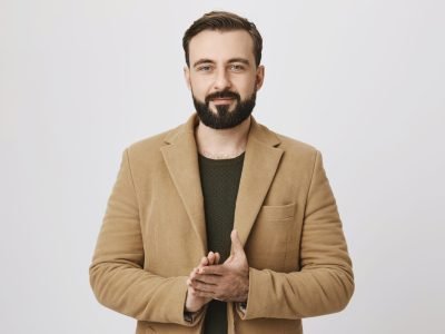 Confident handsome businessman rubbing his hands over white background. Satisfied man already knows that deal with another company will be signed so he feels happy, enjoying this moment.